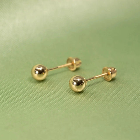 Real 14K Gold Ball Screw Back Stud Earrings For Women And Men 4mm Solid Yellow Gold Hypoallergenic And Hand Polished For Everyday Comfort And All Day Wear, pair on green background
