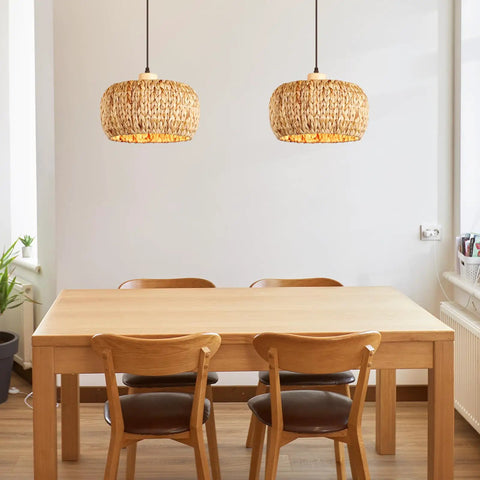 Two hand-woven rattan pendant lights above a wooden dining table, featuring 12 inch wicker shades for farmhouse vibes.