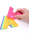 Hand peeling a pink letter from the Neon Poster Letters Set 4 Inch 190 Pieces A To Z, 0 To 9 And Symbols