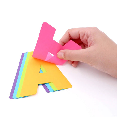 Hand peeling a pink letter from the Neon Poster Letters Set 4 Inch 190 Pieces A To Z, 0 To 9 And Symbols