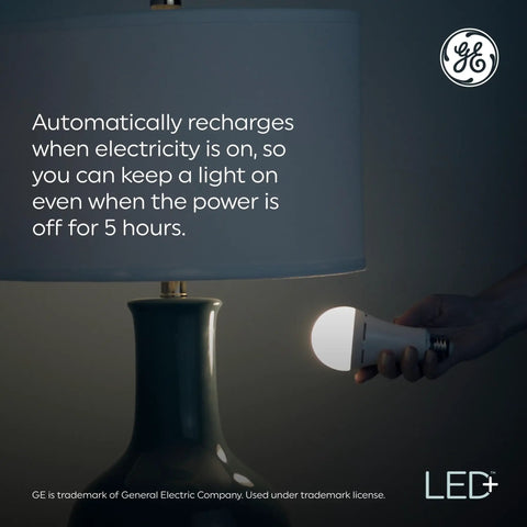 A hand holding Battery Backup A21 LED Light Bulbs with Built In Rechargeable Power Outage Light next to a lit lamp shade.