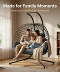 Two Person Outdoor Double Egg Swing Chair With Stand For Patio Or Garden Weather Resistant Hanging Hammock With Cushions Durable And Sturdy Dark Grey Ideal For Cozy Sunset Lounging with a family sitting indoors.