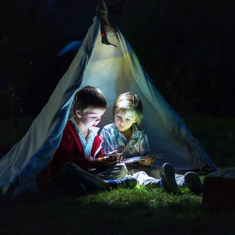 Two children reading under a blanket tent illuminated by the Rechargeable LED Work Light With Magnetic Base And 360 Degree Rotating Head