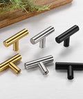 Assortment of T-Bar cabinet knobs in silver, black, and gold on a surface, showcasing diverse finishes.