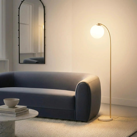 Luna Drop 75 Inch Antique Brass Floor Lamp With Frosted White Glass Globe Shade next to a sofa in a cozy living room