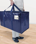 Person carrying Six Pack Extra Large Moving Bags Heavy Duty With Zippers And Carrying Handles Tough As Nails Waterproof Storage Bags For Moving Camping And Closet Organization Navy 27 By 14 By 15 Inches Up To 24 Gallons And 100 Lbs
