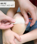 Applying a bandage from 107 Piece Car Emergency Kit For Vehicles With Jumper Cables Mini First Aid Kit Flashlight Tire Pressure Gauge Ice Scraper Escape Hammer Bungee Cords Screwdrivers In Gray Bag Roadside Safety on a child's knee.