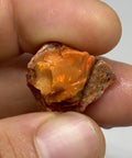 Raw Fiery Jalisco Mexican Fire Opal Stone For Jewelry Making Multicolor Natural Opal Rough Gem With Size 18mm By 16mm By 9mm And Weight 22.60 Ct From Jalisco Mexico Perfect For Beads Cabochons Or Pendant Projects For Unique Jewelry held in hand