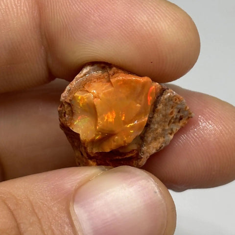 Raw Fiery Jalisco Mexican Fire Opal Stone For Jewelry Making Multicolor Natural Opal Rough Gem With Size 18mm By 16mm By 9mm And Weight 22.60 Ct From Jalisco Mexico Perfect For Beads Cabochons Or Pendant Projects For Unique Jewelry held in hand