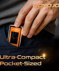 Person placing a COYOJO ultra-compact portable device into a pants pocket. The small size and orange color are visible.