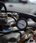 Front view: Astro 7856 universal air-powered cooling system pressure tester connected to car radiator; gauge visible.