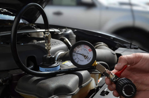 Front view: Astro 7856 universal air-powered cooling system pressure tester connected to car radiator; gauge visible.