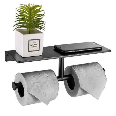 Double Roll Toilet Paper Holder With Shelf Matte Black Brass Finish, holding two rolls, small plant, and phone on the upper shelf