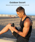 Man using Mini Thermal Massage Gun With Heat Portable Deep Tissue Percussion Massager With Four Heads for leg outdoors.