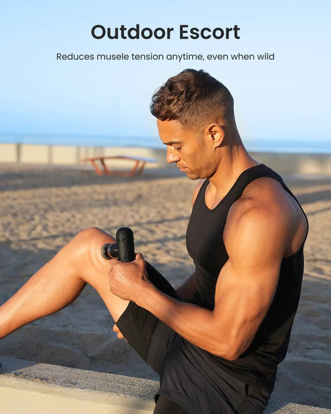 Man using Mini Thermal Massage Gun With Heat Portable Deep Tissue Percussion Massager With Four Heads for leg outdoors.