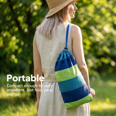 Woman carrying a striped travel bag for Ultra Comfy Cotton Hammock Portable Camping Hammock For Hanging With Tree Straps Sturdy Garden Fabric Hammock Up To 660 Lbs Includes Travel Bag Great For Camping Outdoor Indoor Patio Backyard Relaxation.