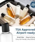 Five TSA Approved Travel Bottles 3.4 Oz on clothes in suitcase, clear plastic containers with labels for shampoo, lotion, gel, perfect for flights.