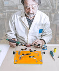 Technician using Pro Grade Six Arm Magnetic Helping Hands Soldering Station with heavy duty base for electronics repair