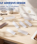 25 Pack Adhesive Base Sign Holders With Strong Backing For Counters And Shelves, Multipurpose Sign Displays For Restaurants, Retail And Warehouses, Easy Peel And Stick, 1 By 3 Inch clear PVC holders on a wooden counter