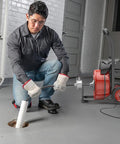 Man using a 100ft auto feed sewer snake machine with 750w power to clear a drain clog in home.