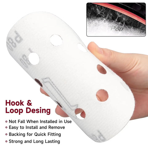 Close-up of a hand holding a 5-inch white sanding disc with holes, part of the 100 Pc 5 Inch Sanding Discs Hook And Loop Kit With 10 Grits From Rough To Fine For Orbital Sander That Makes Woodworking Super Smooth And Quick Without Constant Rebuying.