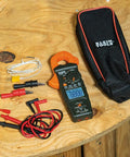 HVAC Clamp Meter All In One With Auto Ranging TRMS And NCVT Inrush And More plus accessories and carrying case on wooden table.