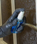 Black nitrile disposable gloves on hand, close-up of spray bottle nozzle
