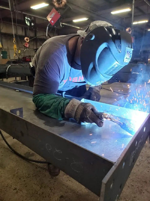 Worker welding in a factory wearing Rugged Leather Palm Gloves With Kevlar Lining Gunn Cut Side Split Design Tough As Nails for safety