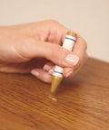 Close-up of hand using Wax Wood Furniture Filler Sticks Scratch Repair Kit With 5 Color Blends And Sharpener on wood surface