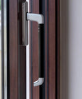 Close-up of a modern black and silver door handle on a wooden door.
