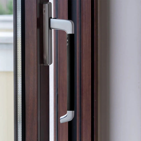Close-up of a modern black and silver door handle on a wooden door.