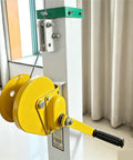 Close-up of yellow manual hand crank winch on white aluminum telescopic mast for antennas and lights.