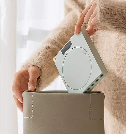 Electric Coffee Mug Warmer For Office Desk With Auto Shut Off Timer being placed in a beige container, highlighting its compact design.