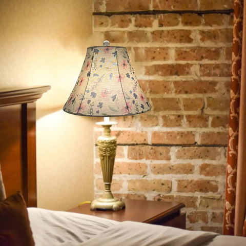 Decorative floral lamp shade on vintage bedside lamp against brick wall