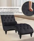 Black velvet upholstered chaise lounge chair with pillow, button tufted armless modern backrest, shown in a living room setting