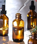 Close-up of 4 Pack 30ml Dark Amber Glass Dropper Bottles With 1 Funnel And 4 Labels, showing a dropper in use with amber bottles.