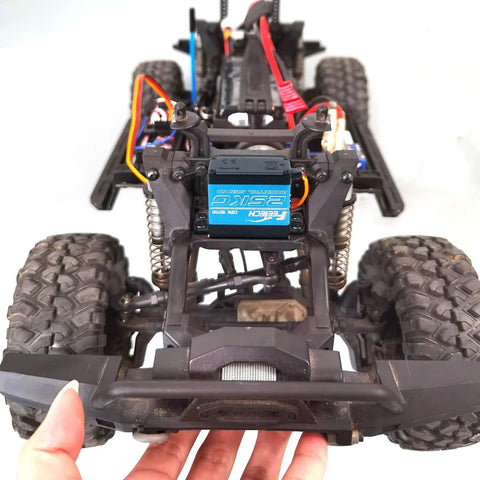 Front view of an off-road RC car chassis featuring a blue Feetech 180° servo motor and coil shocks.