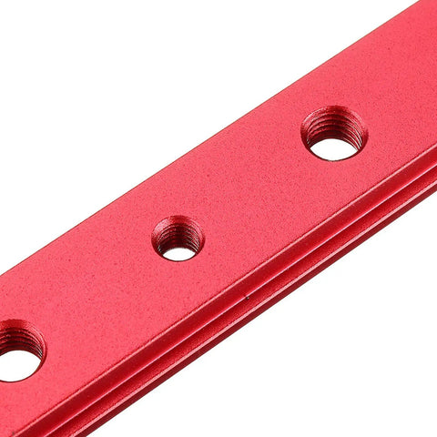 Close-up of red anodized aluminum miter bar slider for T slot table saw track, featuring threaded holes.