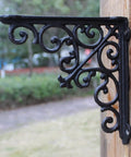 Built Tough Heavy Duty Cast Iron Wall Shelf Brackets Rust Proof 90 Degree Corner Braces with ornate design mounted on wood.