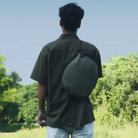 Person carrying a packed Outdoor Camping Hammock With Mosquito Net And Bug Net Dope 13 Foot Parachute Nylon Hammock in a green bag.