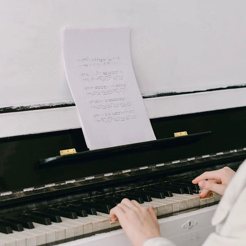Person playing piano with sheet music, golden copper piano hinges holding music stand, for jewelry boxes and wood cabinets