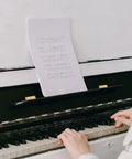 Close-up of hands playing a piano with sheet music, highlighting two Copper Piano Hinges Set for Jewelry Boxes and Cabinets on the music stand.
