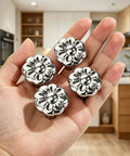 Hand holding Chrome Flower Drawer Knob Set Zinc Cabinet Pulls 4 Pack with durable chrome finish in kitchen setting.