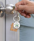 Camper Keychain Gift For RV Lovers And Campers, Travel Trailer Accessory For Men And Women held by a hand in front of a door lock.
