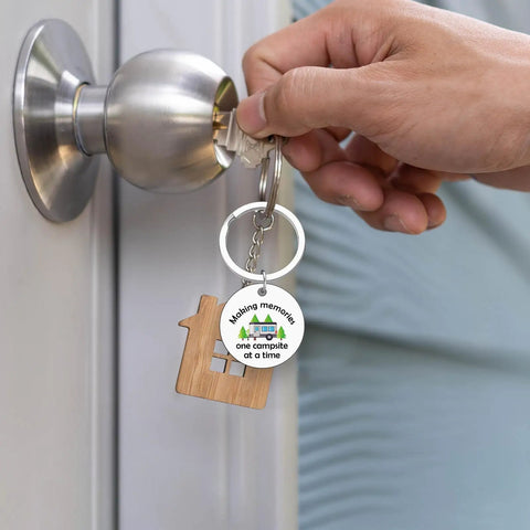 Camper Keychain Gift For RV Lovers And Campers, Travel Trailer Accessory For Men And Women held by a hand in front of a door lock.