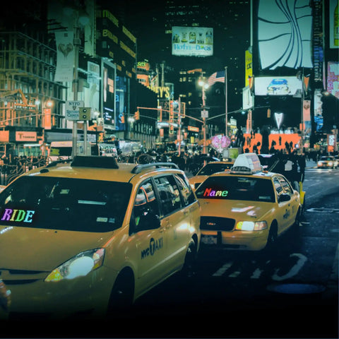 Two yellow taxis with bright city lights in the background, capturing a vibrant night scene with advertising billboards.