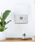 Digital Non Programmable Thermostat With Clear Digital Display And Soft Touch Buttons mounted on wall in modern interior