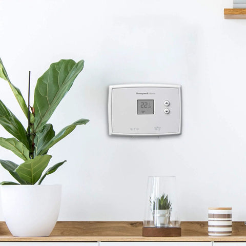 Digital Non Programmable Thermostat With Clear Digital Display And Soft Touch Buttons mounted on wall in modern interior