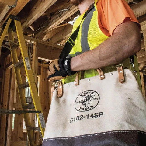 Worker holding Tough As Nails 14 Inch Tool Bag With Detachable Shoulder Strap in construction site, showcasing canvas material.
