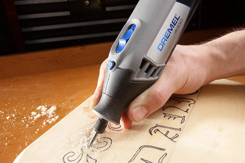 Person using All-Purpose Rotary Tool Accessory Kit With 110 Pieces Including Carving Bit Sanding Drums Grinding Stones Cutting Discs And A Storage Case Gray Ideal For DIY Projects And Home Improvement Tasks to carve wood, close-up.